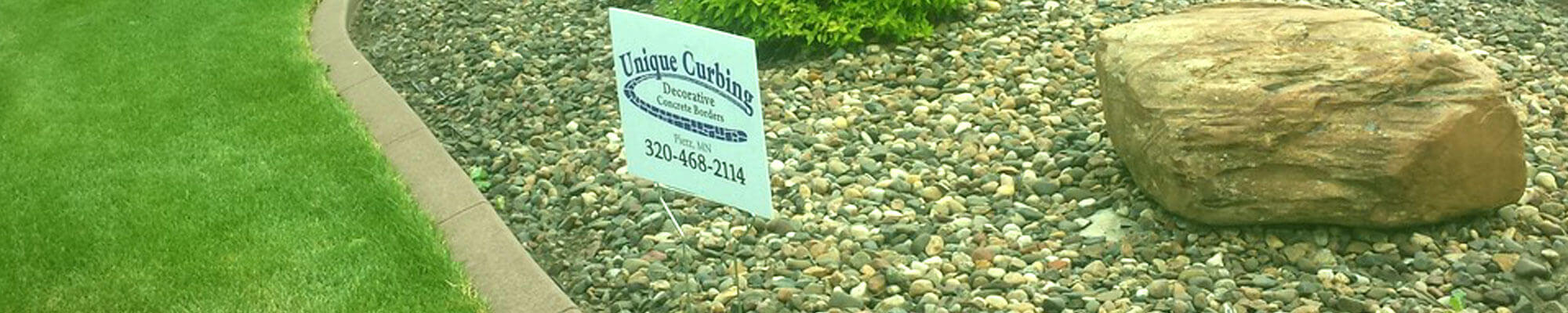 Rock garden edged with a continuous concrete border and showcasing a contractor's sign from Unique Curbing of Pierz, MN