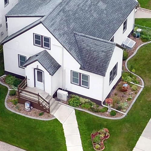 Aerial photo of a home where continuous concrete borders were used to create rock and flower gardens around the entire permiter of the house.